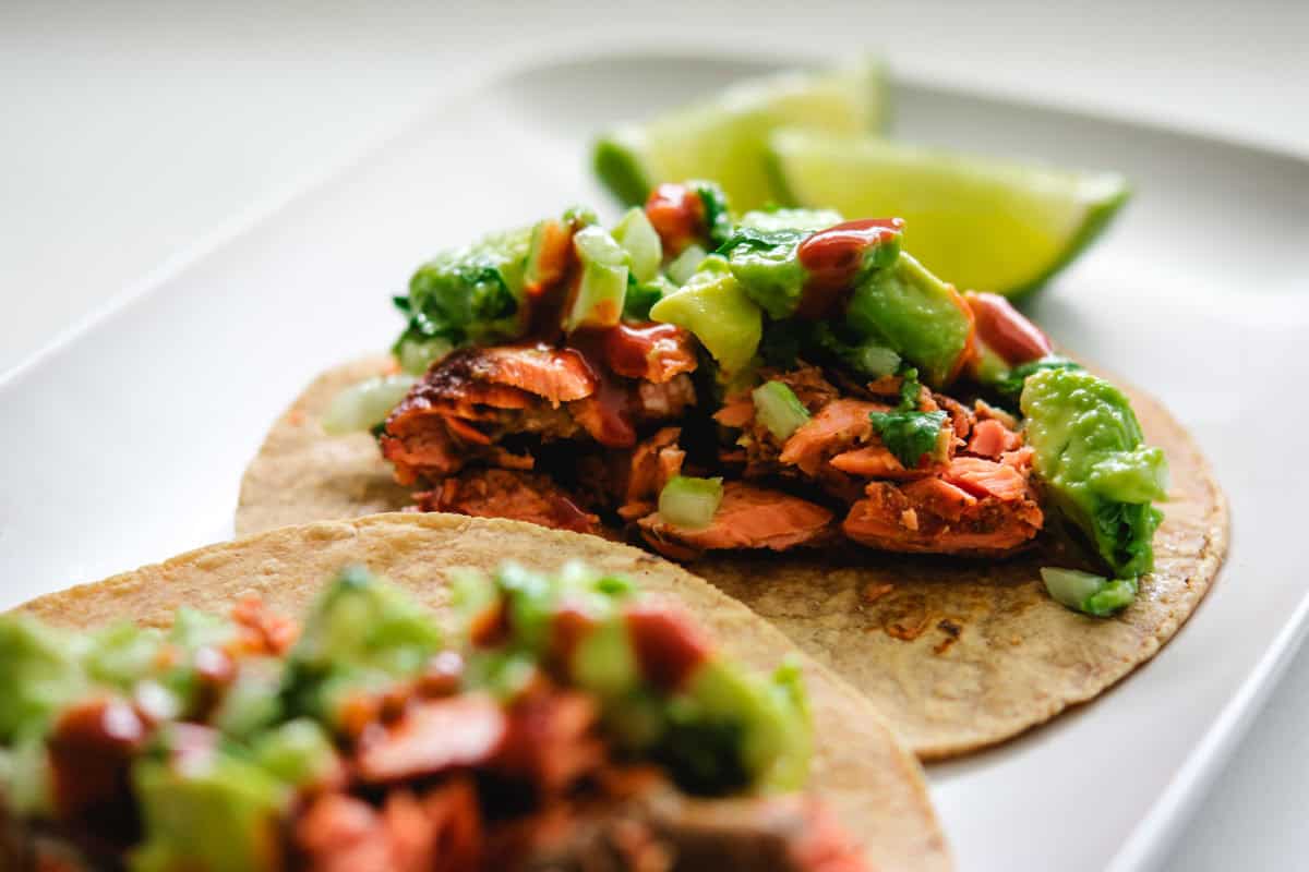 sockeye salmon taco on a rectangular grey plate with 2 lime wedges