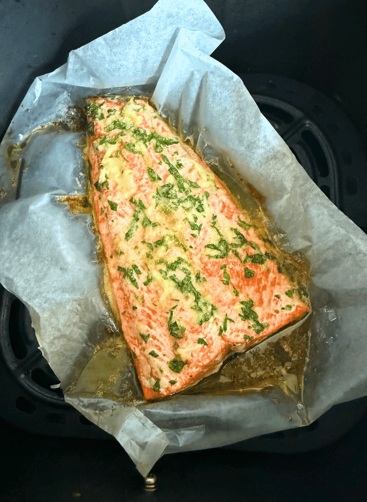 Air Fryer Sockeye Salmon with Creamy Garlic Butter in an air fryer baasket with parchment paper