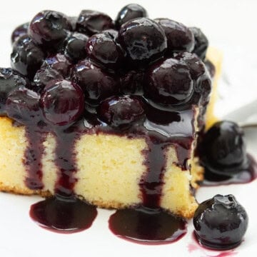 Blueberry sauce on a cornmeal cake with a fork on a white plate