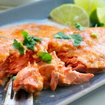 Thai Red Curry sockeye salmon with cilantro garnish and lime wedges