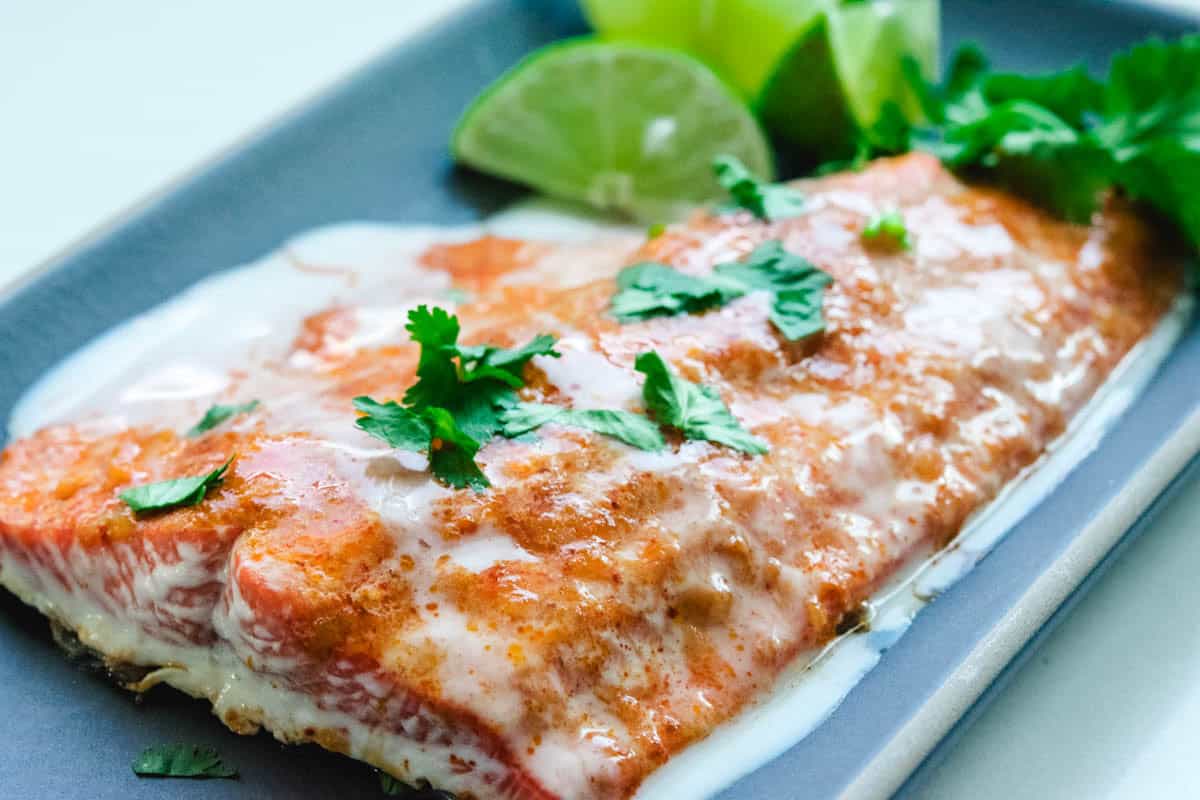 Thai Red Curry sockeye salmon with cilantro garnish and lime wedges