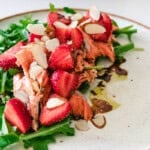 Sockeye salmon and strawberry salad on a white plate with sliced almonds