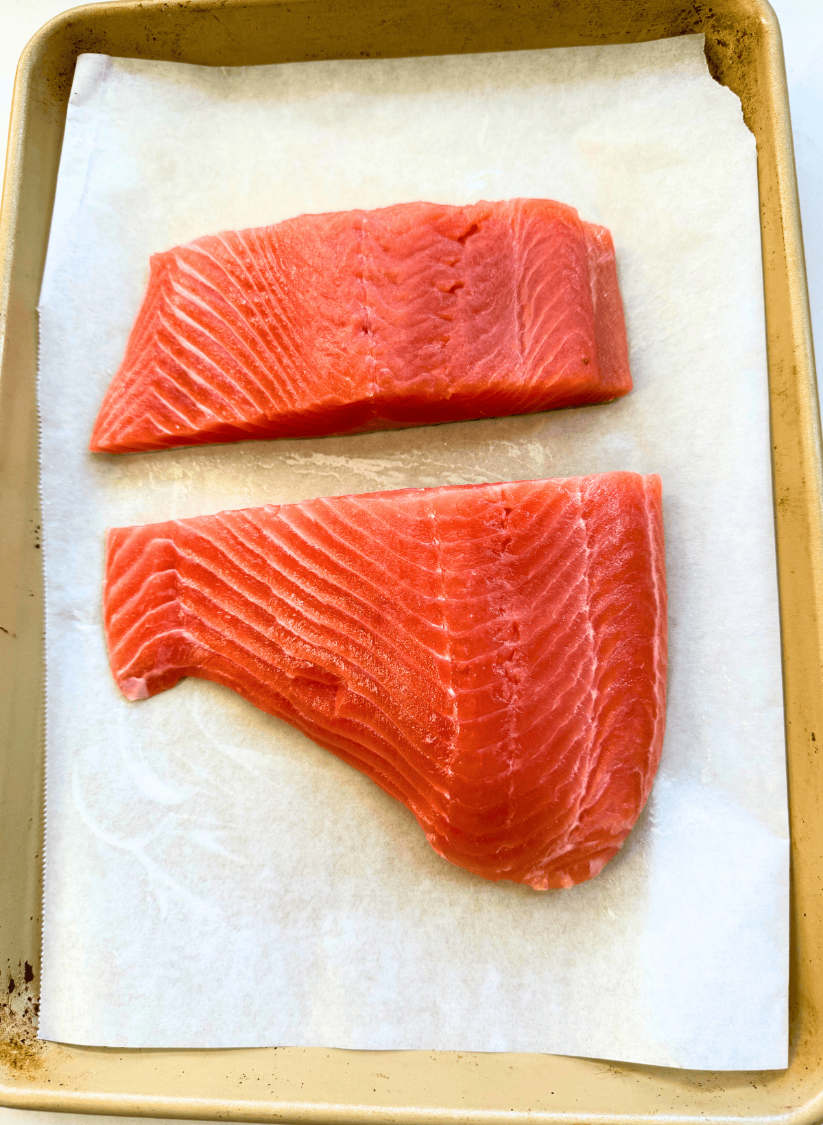 2 filets of king salmon on a parchment lined gold baking sheet