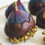 Chocolate covered mission figs with pistachios on a round white plate