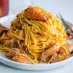 pink oyster mushroom pasta on a round white plate with a fork