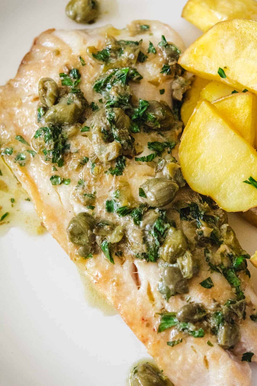 filet of sauteed rockfish with a side of roasted potatoes on a white round plate