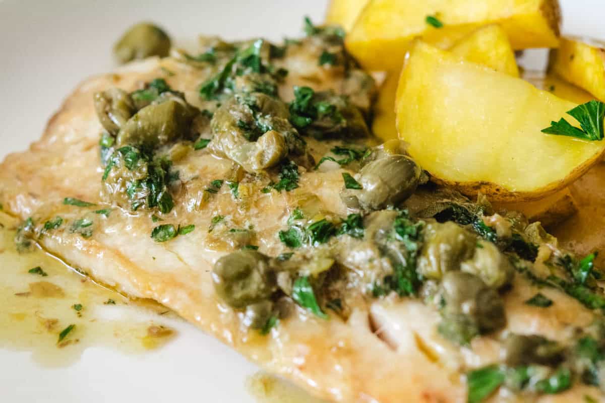 filet of sauteed rockfish with a side of roasted potatoes on a white plate