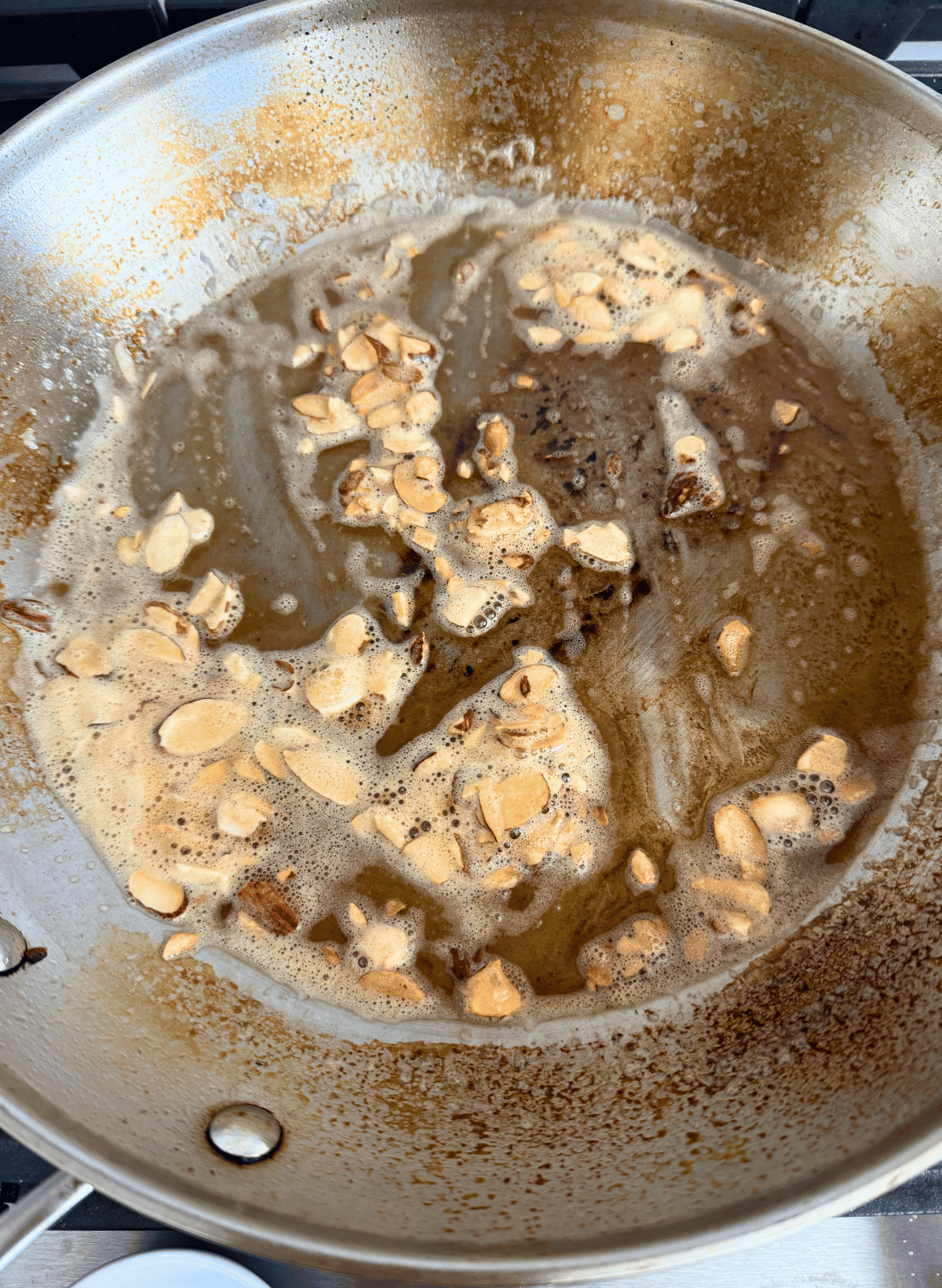 stainless steel skillet with sliced almonds toasting in butter