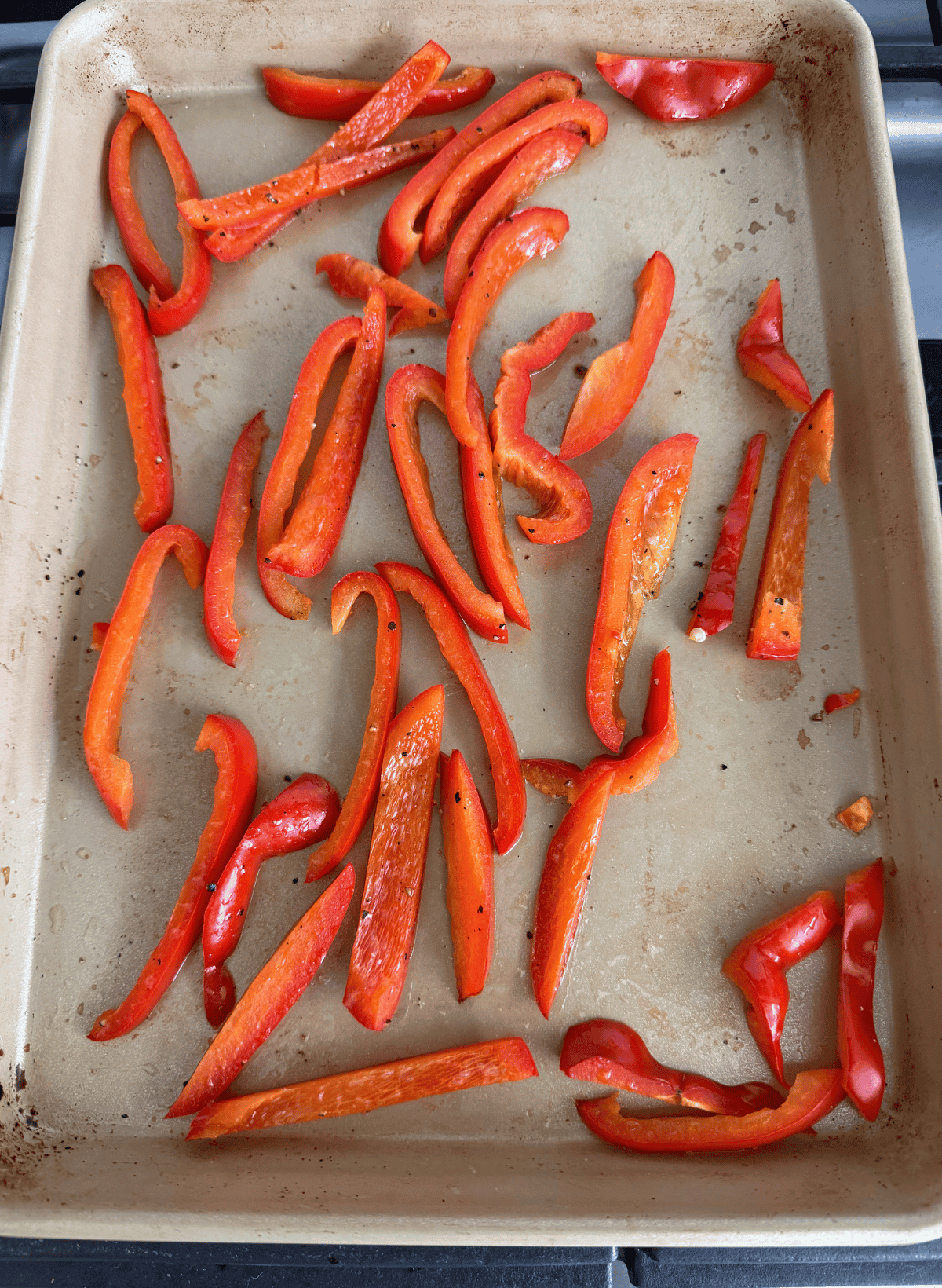 red bell peppers strips on a gold sheet pan