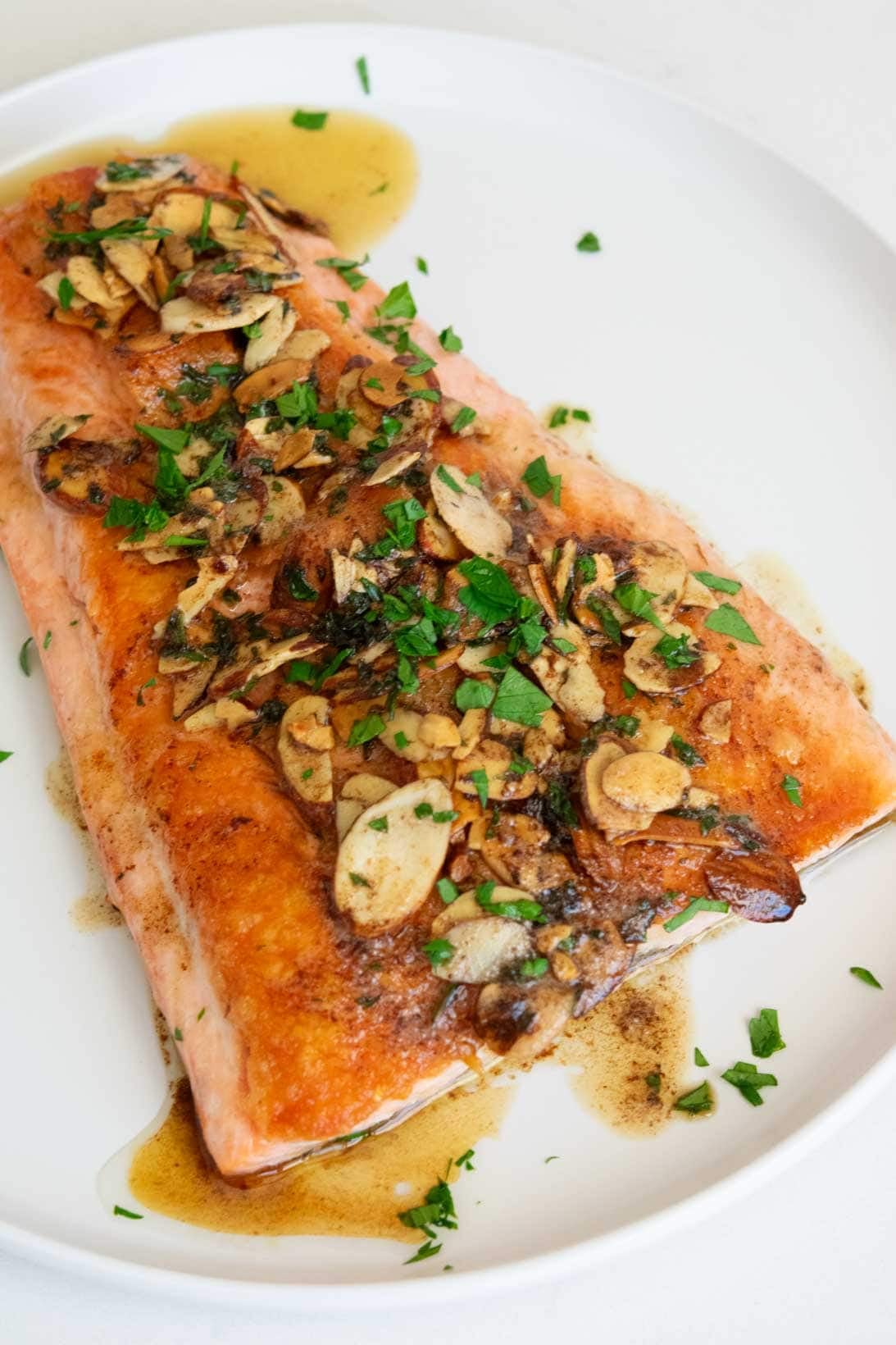 one large fillet of salmon almondine on a white round plate