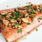 one large fillet of salmon almondine on a white round plate
