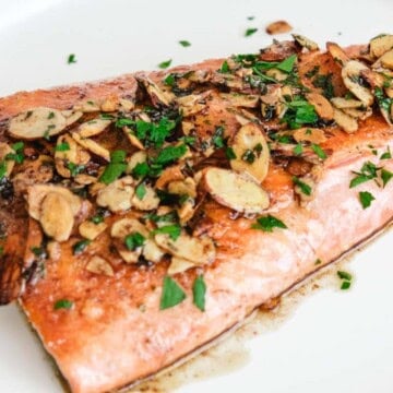 one large fillet of salmon almondine on a white round plate