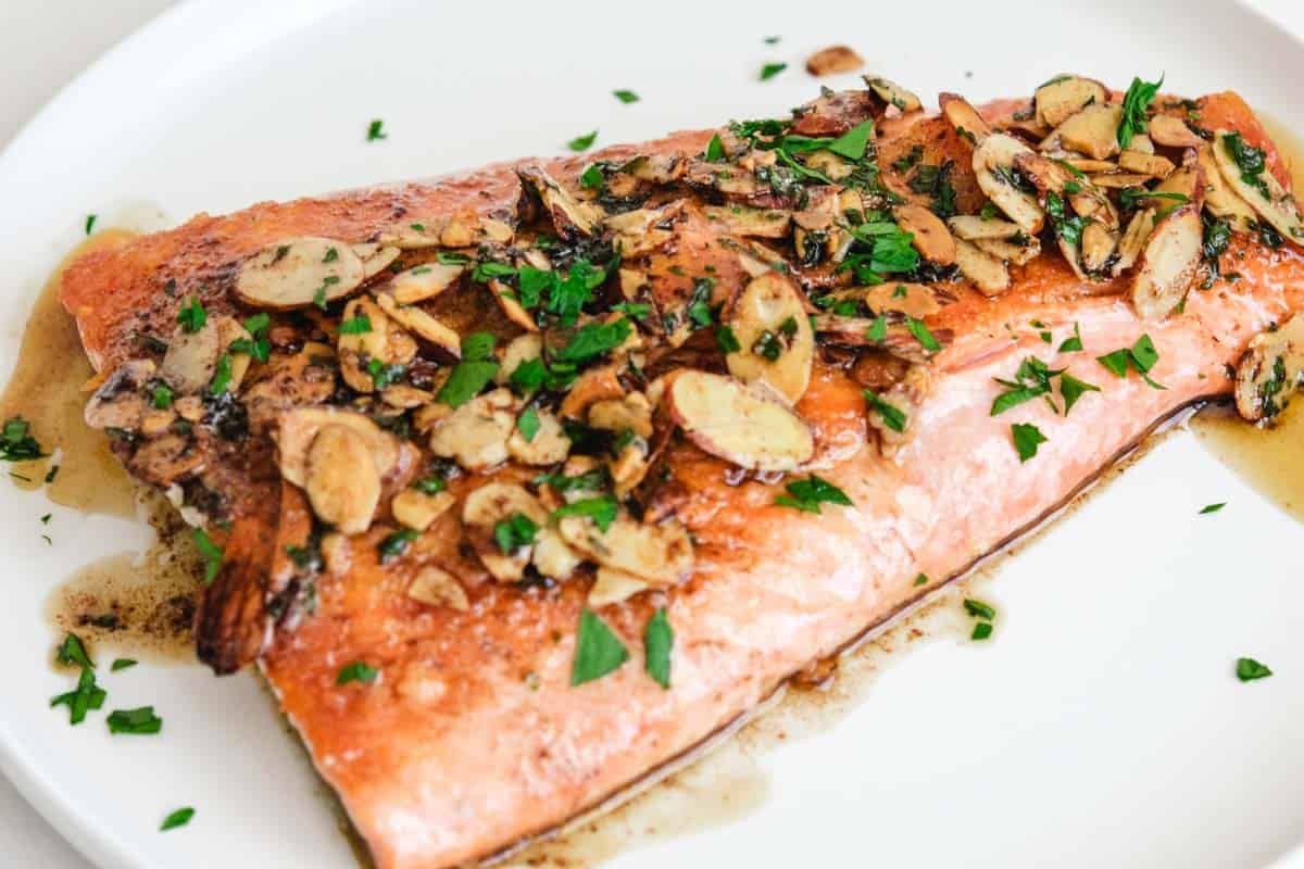 one large fillet of salmon almondine on a white round plate