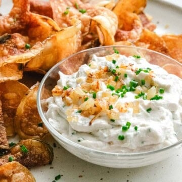 vegan onion dip with potato chips on a round white plate