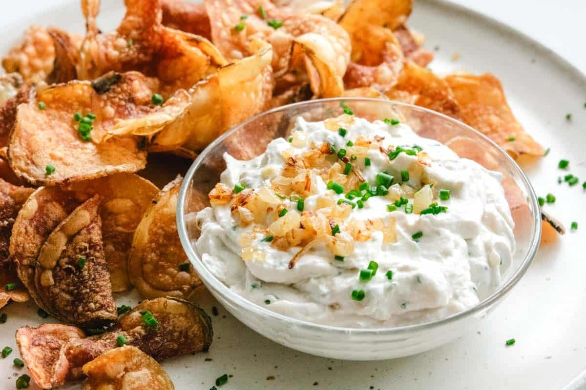 vegan onion dip with potato chips on a round white plate