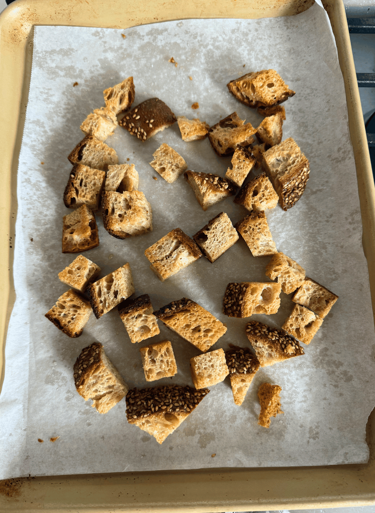 toasted whole wheat croutons on a parchment lined gold baking sheet