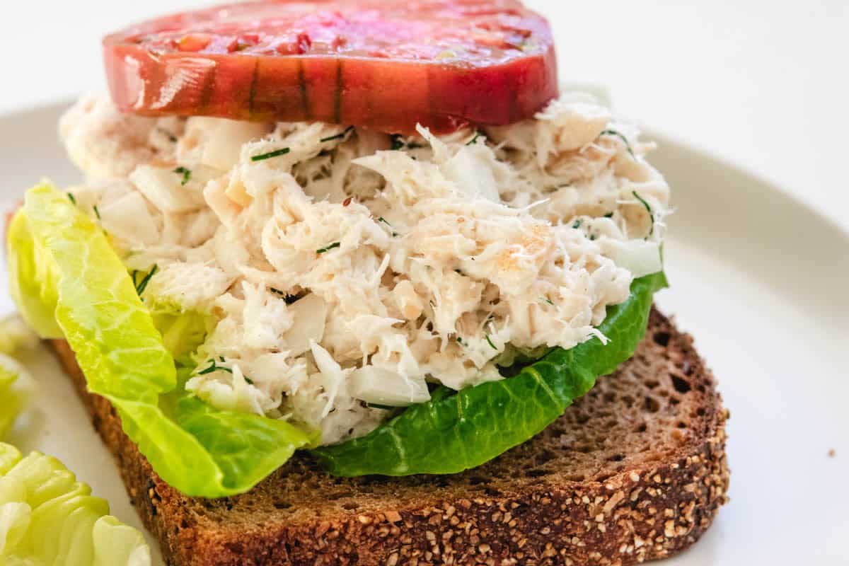rockfish salad on whole wheat bread with lettuce and a slice of tomato