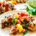 rockfish tacos with hot sauce with lime wedges and cilantro in the background