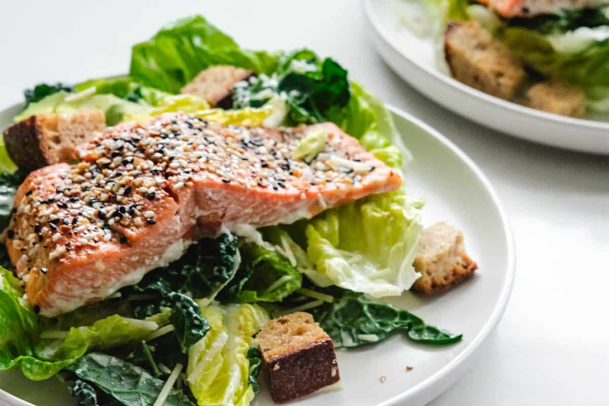 Coho salmon caesar salad on a white round plate