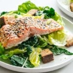 Coho salmon caesar salad on a white round plate