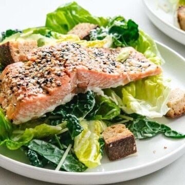 Coho salmon caesar salad on a white round plate